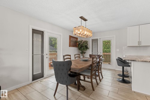 Dining area featuring light-toned tile flooring and a decorative rectangular chandelier - 34 Stirling Road Nw, Edmonton, AB - Indoor Photo Showing Dining Room