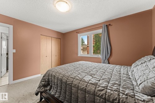 Carpeted room featuring a window with white trim, a flush mount ceiling light, and bi-fold closet doors - 34 Stirling Road Nw, Edmonton, AB - Indoor Photo Showing Bedroom