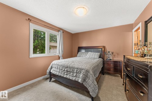 Carpeted room featuring a white-trimmed window, a flush-mount ceiling light, and a doorway with white casing - 34 Stirling Road Nw, Edmonton, AB - Indoor Photo Showing Bedroom