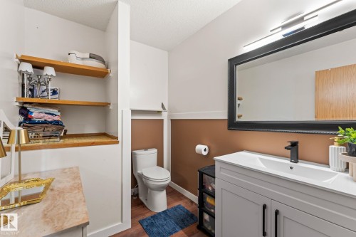 Bathroom featuring a white vanity with integrated sink, black framed mirror, and modern light fixture - 34 Stirling Road Nw, Edmonton, AB - Indoor Photo Showing Bathroom