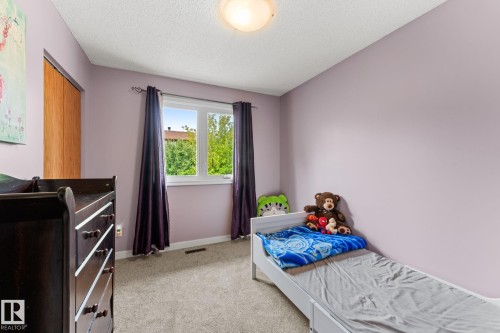 Carpeted interior room featuring light purple walls and a single window with purple drapes - 34 Stirling Road Nw, Edmonton, AB - Indoor Photo Showing Bedroom
