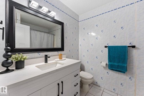Bathroom vanity featuring a white countertop with integrated sink and a matte black faucet - 34 Stirling Road Nw, Edmonton, AB - Indoor Photo Showing Bathroom