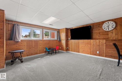 Spacious room featuring wood paneling, light gray carpeting, and multiple windows - 34 Stirling Road Nw, Edmonton, AB - Indoor Photo Showing Other Room