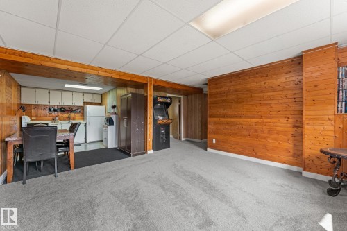 Spacious lower level featuring wood paneling, light gray carpeting, and a drop ceiling with fluorescent lighting - 34 Stirling Road Nw, Edmonton, AB - Indoor