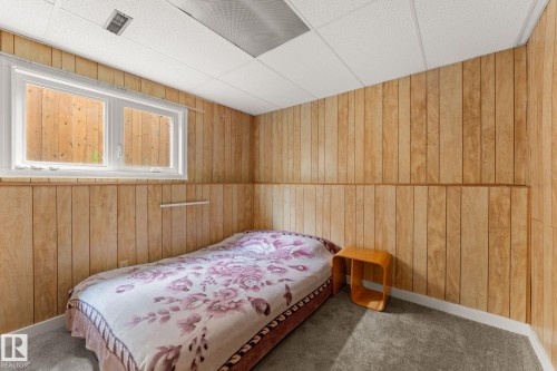 Room featuring wood paneling, drop ceiling, and a white framed window - 34 Stirling Road Nw, Edmonton, AB - Indoor Photo Showing Bedroom