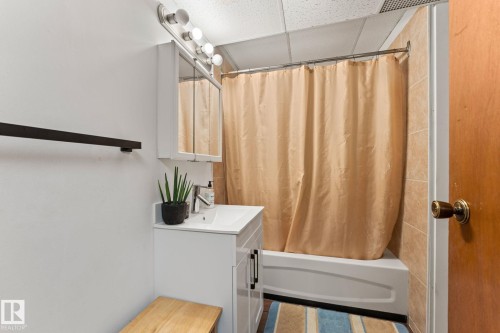 Bathroom featuring a white vanity with integrated sink, chrome faucet, and a wall-mounted medicine cabinet with mirrored doors - 34 Stirling Road Nw, Edmonton, AB - Indoor