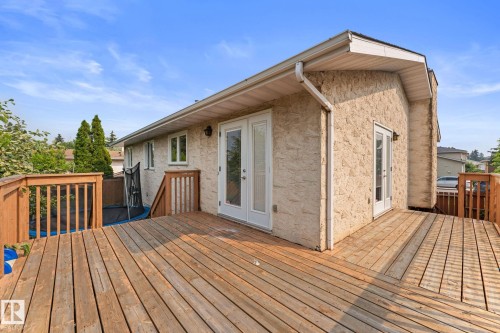 Expansive wood deck with natural wood railing, multiple access points via French doors, and textured exterior siding - 34 Stirling Road Nw, Edmonton, AB - Outdoor With Deck Patio Veranda With Exterior