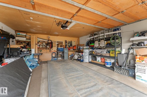 Attached garage space featuring a concrete floor, overhead garage door with opener, and integrated wall shelving - 34 Stirling Road Nw, Edmonton, AB - Indoor Photo Showing Garage