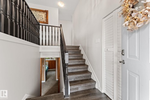 Split-level entry featuring wood-finish flooring, dark wood newel posts, and balusters - 34 Stirling Road Nw, Edmonton, AB - Indoor Photo Showing Other Room