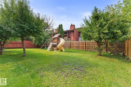 Spacious backyard featuring a large grassy area, mature trees, and a full privacy fence - 34 Stirling Road Nw, Edmonton, AB - Outdoor