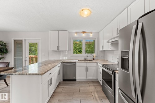 Kitchen featuring white cabinetry, light-colored countertops, stainless steel appliances, and tile flooring - 34 Stirling Road Nw, Edmonton, AB - Indoor Photo Showing Kitchen With Upgraded Kitchen