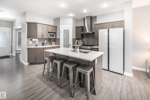 Kitchen featuring wood-finish flooring, recessed lighting, and a center island with a sink and white countertop - 16015 11 Avenue Sw, Edmonton, AB - Indoor Photo Showing Kitchen With Double Sink
