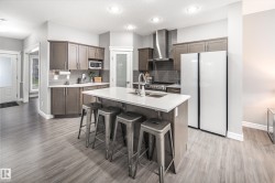 Kitchen featuring wood-finish flooring, recessed lighting, and a center island with a sink and white countertop - 