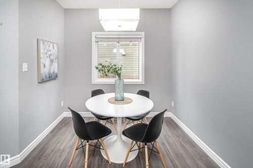 Recessed dining area featuring wood-finish flooring, a white window with blinds, and an overhead rectangular light fixture - 16015 11 Avenue Sw, Edmonton, AB - Indoor Photo Showing Dining Room