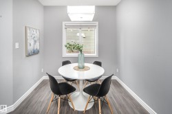 Recessed dining area featuring wood-finish flooring, a white window with blinds, and an overhead rectangular light fixture - 