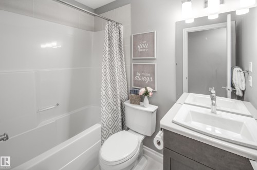 White shower-tub combination, single vanity with integrated sink, chrome faucet, and gray wood-finish cabinetry - 16015 11 Avenue Sw, Edmonton, AB - Indoor Photo Showing Bathroom