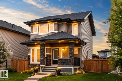 Two-story home with stone column accents, neutral-toned siding, and a dark shingle roof - 16015 11 Avenue Sw, Edmonton, AB - Outdoor