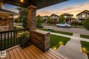 Inviting front porch with wood-finish decking and stone veneer columns - 16015 11 Avenue Sw, Edmonton, AB  - Outdoor With Exterior 