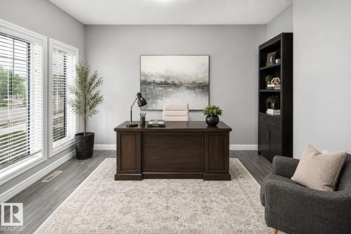 Spacious room featuring two large windows, wood-finish flooring, and a built-in bookshelf - 16015 11 Avenue Sw, Edmonton, AB - Indoor Photo Showing Office