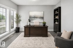 Spacious room featuring two large windows, wood-finish flooring, and a built-in bookshelf - 