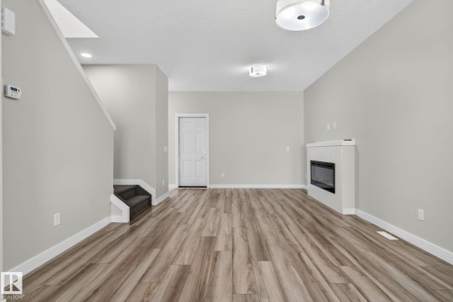 Wood-finish flooring, white trim, and light gray walls complement the built-in electric fireplace - 4879 Alwood Point(E) Sw, Edmonton, AB - Indoor With Fireplace