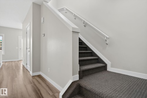 Staircase featuring patterned carpet treads and white handrails - 4879 Alwood Point(E) Sw, Edmonton, AB - Indoor Photo Showing Other Room