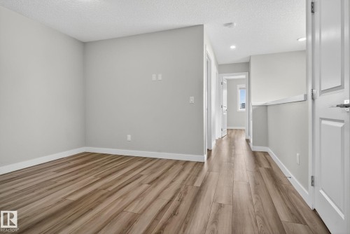 Light gray walls, wood-finish flooring, white doors, recessed lighting, and a window providing natural light - 4879 Alwood Point(E) Sw, Edmonton, AB - Indoor Photo Showing Other Room