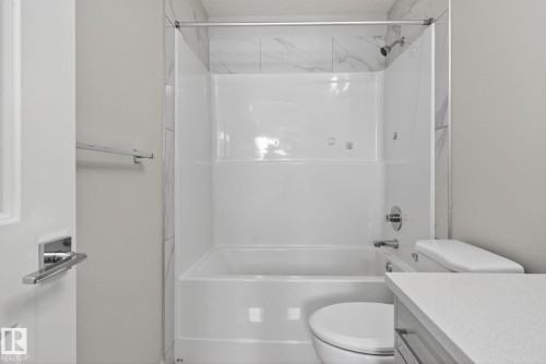 Tub and shower combination with chrome fixtures and a shower curtain rod - 4879 Alwood Point(E) Sw, Edmonton, AB - Indoor Photo Showing Bathroom