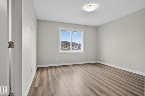 Light gray wall paint, wood-finish flooring, white window trim, white baseboards, and a semi-flush mount ceiling light - 4879 Alwood Point(E) Sw, Edmonton, AB - Indoor Photo Showing Other Room