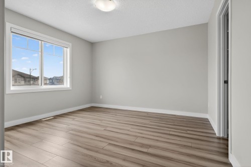 Wood-finish flooring, neutral wall tones, and a window with white trim - 4879 Alwood Point(E) Sw, Edmonton, AB - Indoor Photo Showing Other Room