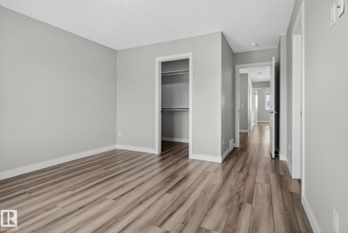 Light gray painted walls with white trim, wood-finish flooring, and an open closet with shelving and hanging rods - 4879 Alwood Point(E) Sw, Edmonton, AB - Indoor Photo Showing Other Room