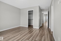 Light gray painted walls with white trim, wood-finish flooring, and an open closet with shelving and hanging rods - 