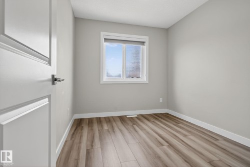 Light-toned walls, wood-finish flooring, white trim, and a white window frame with roller shade - 4879 Alwood Point(E) Sw, Edmonton, AB - Indoor Photo Showing Other Room