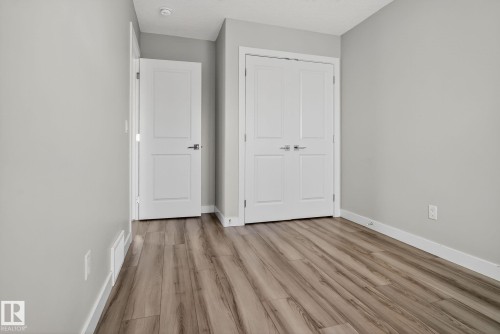 Light-toned walls, wood-finish flooring, white doors with panel detailing, and recessed ceiling lighting - 4879 Alwood Point(E) Sw, Edmonton, AB - Indoor Photo Showing Other Room