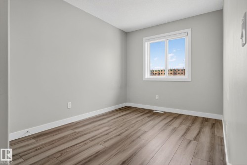 Wood-finish flooring, white window trim, and light grey wall paint - 4879 Alwood Point(E) Sw, Edmonton, AB - Indoor Photo Showing Other Room
