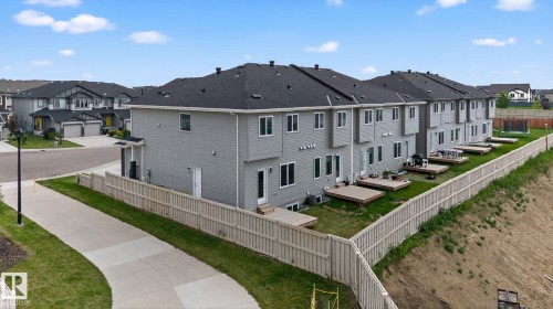 Townhome exteriors featuring light gray siding, white trim windows, and individual ground-level decks - 4879 Alwood Point(E) Sw, Edmonton, AB - Outdoor