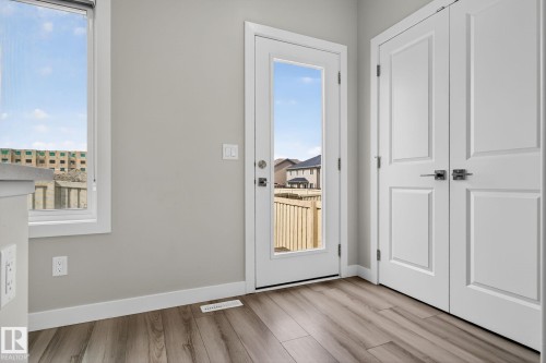 Wood-finish flooring, white trim, light-colored walls, white paneled doors, and a glass-paneled exterior door - 4879 Alwood Point(E) Sw, Edmonton, AB - Indoor Photo Showing Other Room