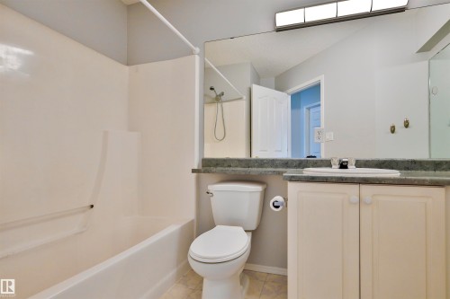 Integrated tub and shower combination, vanity with an undermount sink, countertop, and a large wall-mounted mirror - 15529 95 Avenue Nw, Edmonton, AB - Indoor Photo Showing Bathroom