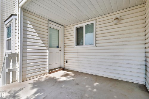 Covered exterior patio featuring a concrete surface, white siding, and an attached exterior light fixture - 15529 95 Avenue Nw, Edmonton, AB - Outdoor With Exterior