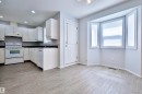 White cabinetry with dark countertops, white appliances, wood-finish flooring, and a bay window - 15529 95 Avenue Nw, Edmonton, AB  - Indoor Photo Showing Kitchen 
