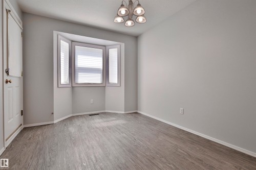 Bay window with integrated blinds, wood-finish flooring, and a five-light chandelier - 15529 95 Avenue Nw, Edmonton, AB - Indoor Photo Showing Other Room