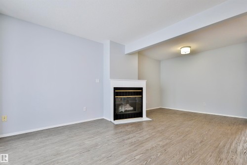 Fireplace with a white mantel, wood-finish flooring, and recessed ceiling light fixture - 15529 95 Avenue Nw, Edmonton, AB - Indoor With Fireplace
