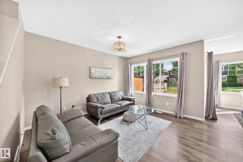 Warmly painted walls and wood-finish flooring define this living space - 5147 Crabapple Link Sw, Edmonton, AB - Indoor Photo Showing Living Room