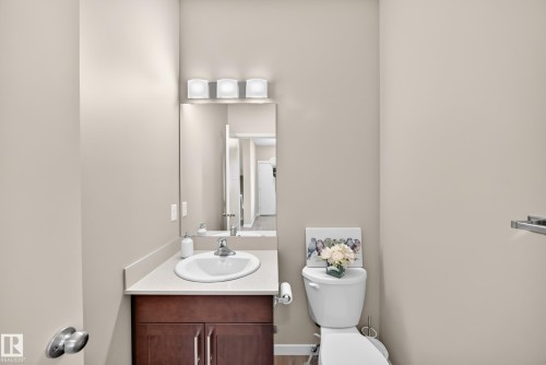 Single vanity with a recessed sink, wood-finish cabinetry, and a full-width mirror - 5147 Crabapple Link Sw, Edmonton, AB - Indoor Photo Showing Bathroom