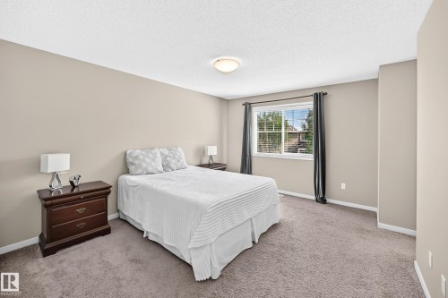 Neutral tone wall paint, textured ceiling, carpet flooring, window with blinds, and curtain rods - 5147 Crabapple Link Sw, Edmonton, AB - Indoor Photo Showing Bedroom