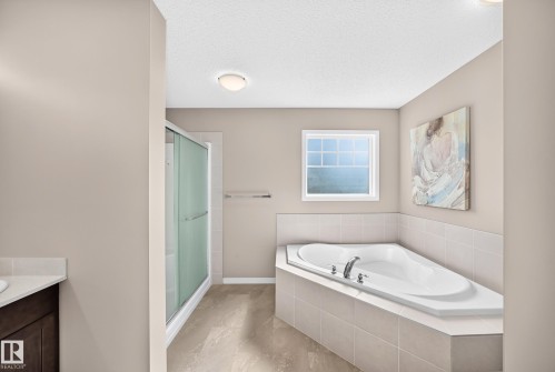 Built-in corner soaking tub with tile surround, separate shower enclosure with sliding glass doors, white framed window, and recessed lighting - 5147 Crabapple Link Sw, Edmonton, AB - Indoor Photo Showing Bathroom
