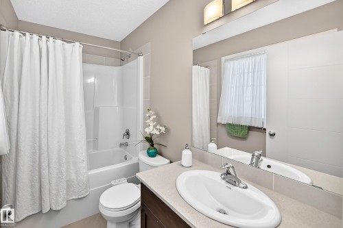 Spa-inspired bathroom featuring dual vanities with white vessel sinks, wood-finish cabinetry, and polished chrome faucetry - 5147 Crabapple Link Sw, Edmonton, AB - Indoor Photo Showing Bathroom