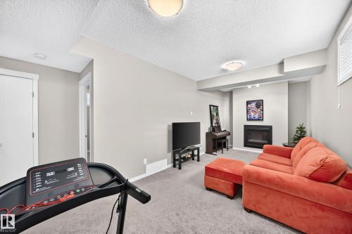 Recessed fireplace with hearth, soft gray wall tones, ceiling-mounted light fixtures, and white trim - 5147 Crabapple Link Sw, Edmonton, AB - Indoor With Fireplace