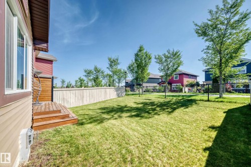 Expansive grassy yard with a wooden privacy fence, mature trees, and a multi-level wooden deck - 5147 Crabapple Link Sw, Edmonton, AB - Outdoor
