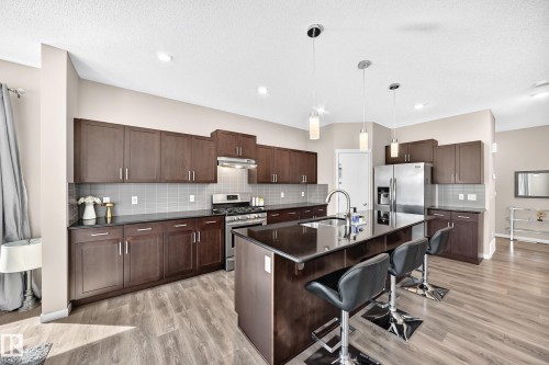 Contemporary kitchen featuring a dark wood-finish island with a built-in sink and pendant lighting - 5147 Crabapple Link Sw, Edmonton, AB - Indoor Photo Showing Kitchen With Double Sink With Upgraded Kitchen